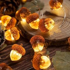 some lights that are sitting on top of a wooden table next to leaves and pine cones