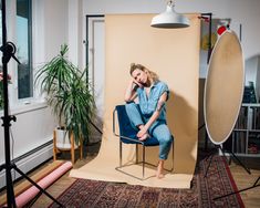 a woman sitting on a chair in front of a photo shoot with a camera and lighting equipment