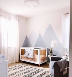 a baby's room with mountains painted on the wall and a crib in the corner