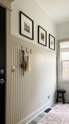 a hallway with pictures on the wall and a coat rack in front of a door