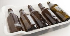 six empty beer bottles in a white container