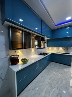 a large kitchen with blue cabinets and white counter tops is lit by recessed lights