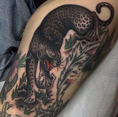 a black panther tattoo on the right arm and leg, with green leaves around it