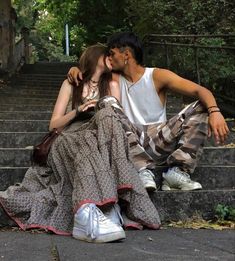 a man and woman sitting on the steps in front of some stairs with their faces close to each other