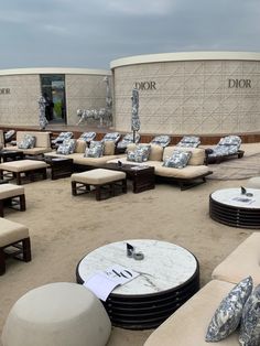 an outdoor seating area with couches, tables and umbrellas in front of a dior store