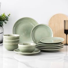 a table topped with plates and bowls next to a vase