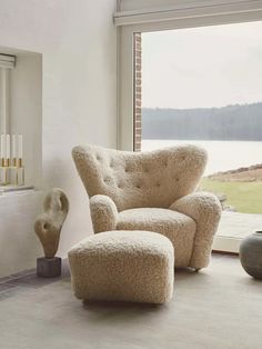 a living room with a chair and ottoman in front of a window overlooking the water