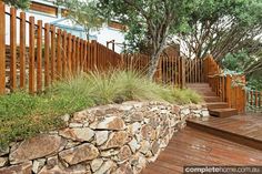 there is a stone wall and wooden steps leading up to the deck area with grass growing on it