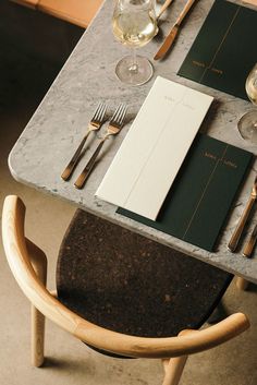 the table is set with wine glasses, silverware and menus for two people