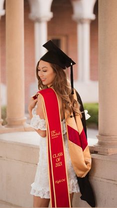 a woman wearing a graduation cap and gown is leaning against a wall with her diploma