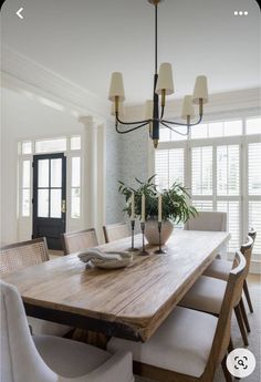 a dining room table with white chairs and a potted plant on the centerpiece