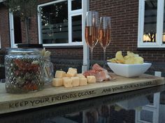 a table with wine glasses and snacks on it next to a brick building in the background