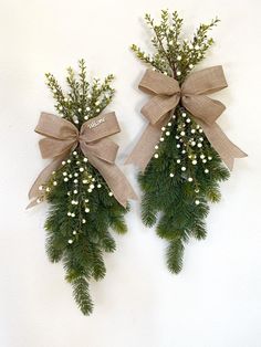 two christmas wreaths with bows and baby's breath are hanging on the wall