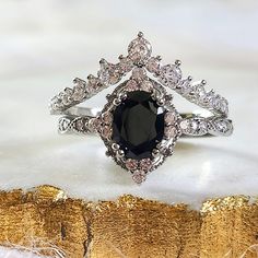 a black and white diamond ring sitting on top of a piece of wood