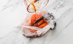 someone pouring orange juice on some food in a plastic bag