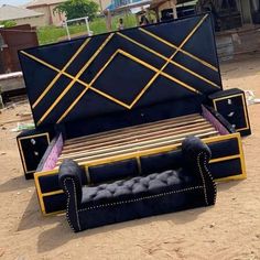 a black and gold couch sitting in the middle of a dirt field next to a wooden bench