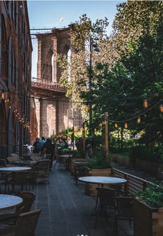 an outdoor patio with tables and chairs next to the brooklyn bridge