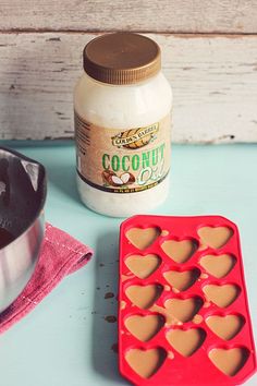 there are heart shaped chocolates in the pan next to an empty cookie sheet and a container of coconut oil