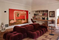 a living room filled with lots of furniture and paintings on the wall above it's fireplace