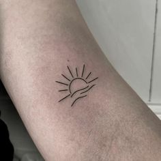 a small sun tattoo on the arm