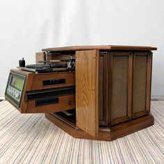 an old fashioned record player sitting on top of a wooden stand with its door open