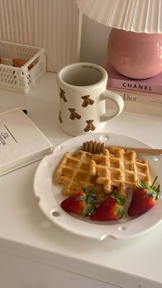 a white plate topped with waffles and strawberries next to a cup of coffee