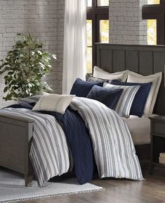 a bed with blue and white striped comforters in a room next to a window