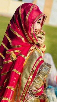 a woman in a red and gold costume is talking on her cell phone while sitting down