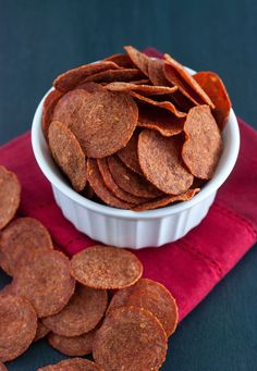 a white bowl filled with chips on top of a red napkin