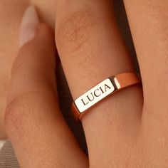 a close up of a person's hand wearing a ring with the word lucia on it