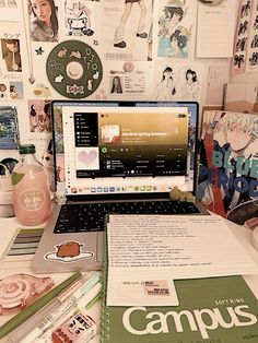 an open laptop computer sitting on top of a desk next to papers and other items