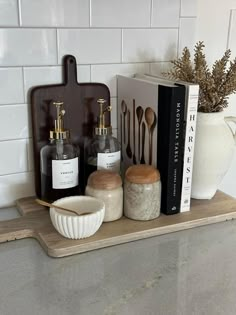 some bottles and spoons sitting on a shelf in a kitchen next to a book