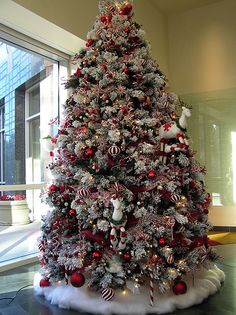 a christmas tree decorated with red and white ornaments in an office building's lobby