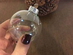 a hand holding a glass ornament in front of a ball on a table