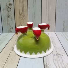 a green and white tray with three red cups on it sitting on a wooden table