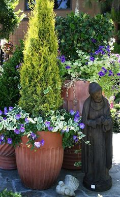 a statue sitting next to two large potted plants