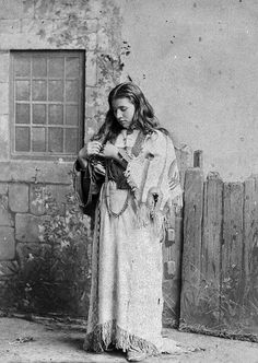 an old black and white photo of a woman in native dress holding a baby bird