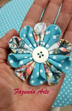 a hand holding a blue and white flower with polka dots on the bottom, in front of a turquoise background