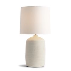 a white table lamp with a beige shade on the base and a white linen lampshade