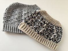 two crocheted hats sitting next to each other on top of a white table