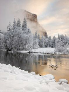 a river surrounded by snow covered trees and mountains