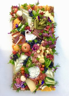 a letter made out of fruits, vegetables and cheeses on a white background is shown