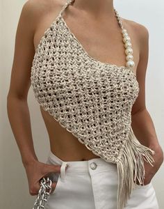 a woman wearing a crochet halter top with pearls on the bottom and a chain around her neck