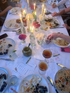 a group of people sitting at a table with plates of food and candles in front of them