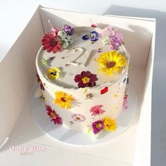 a white cake with colorful flowers on it in a box for someone's 30th birthday