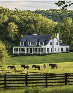 horses graze in front of a large white house surrounded by trees and green grass