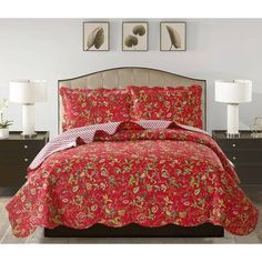 a bed with red bedspread and matching comforter in a white room next to two lamps