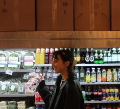 a woman standing in front of a shelf filled with drinks