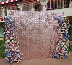 a pink sequin backdrop with blue and white flowers on the side for a wedding ceremony