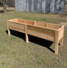 a wooden planter box sitting on top of a grass covered field next to a building